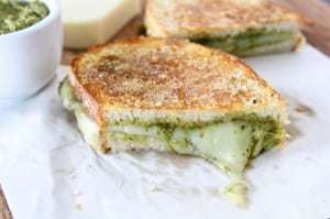 Side view of parmesan crusted pesto grilled cheese cut in half, side by side. 