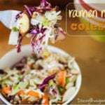 Close up shot of fork holding up ramen noodle coleslaw in a white bowl on a wooden table.