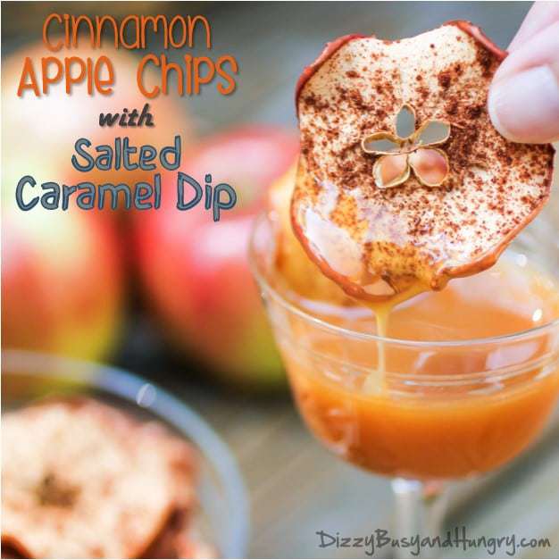 Close up of cinnamon apple chip being dipped into salted caramel dip with apples in the background. 