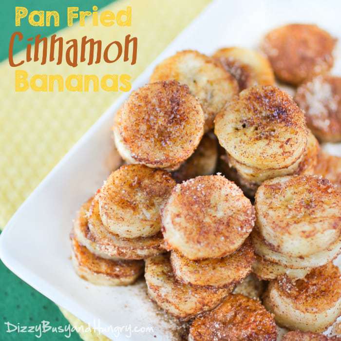 Close up view of pan fried cinnamon bananas on a white plate on a yellow and green cloth. 