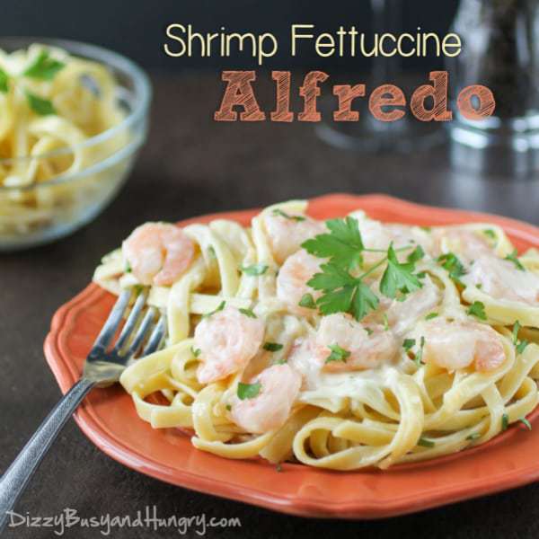 shrimp alfredo on a coral plate with fettuccine and garnished with parsley