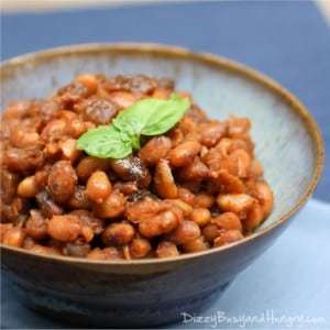 Side shot of boston baked beans garnished with herbs in a blue and orange bowl.