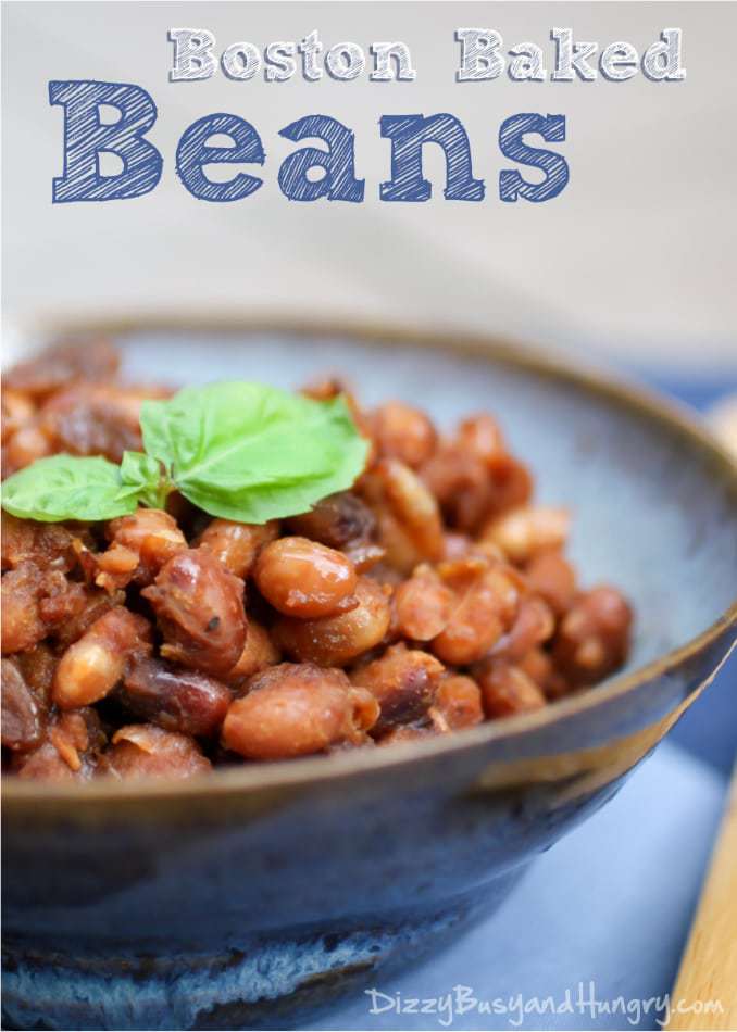 Close up shot of Boston baked beans garnished with herbs in a rustic blue bowl and a blue background. 