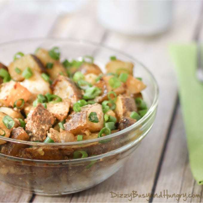 Side shot of chipotle and garlic grilled potatoes in a clear bowl on a green cloth. 