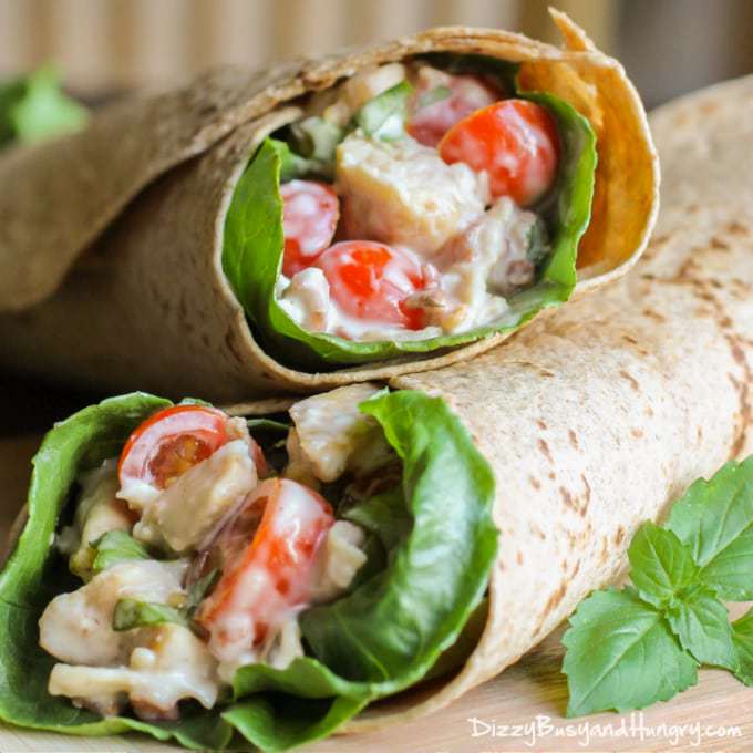 Close up shot fo two bacon blue cheese chicken wraps layer on top of each other with herbs on the side.