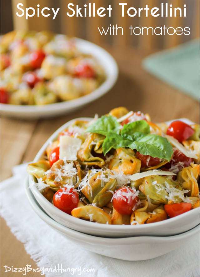 Side view of spicy skillet tortellini in a white bowl garnished with herbs. 