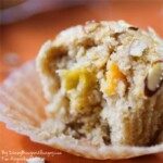 Side view of mango muffin in the liner on an orange cloth.