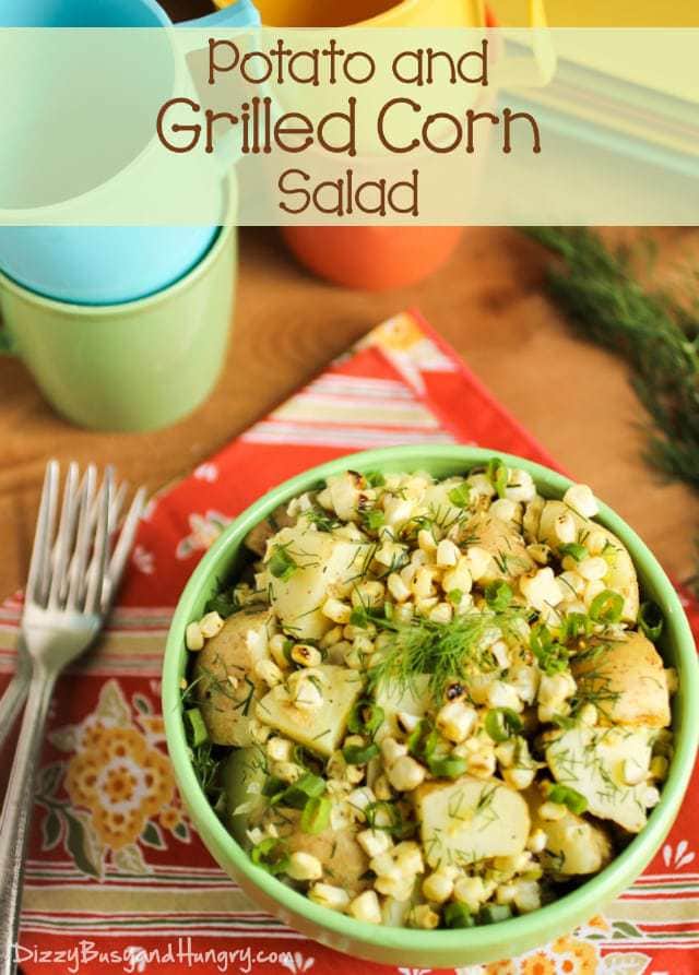 Side shot of potato and grilled corn salad in a green bowl on a red cloth with silverware on the side. 