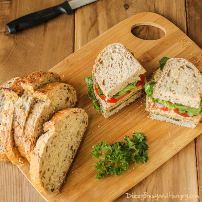 Side view of eggplant Milanese torta cut in half on a wooden cutting board with more sliced bread on the side. 