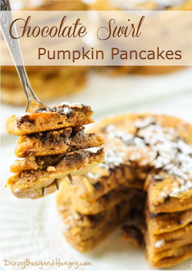 Side view of a fork taking a slice of pumpkin chocolate swirl pancakes stacked on a white plate. 