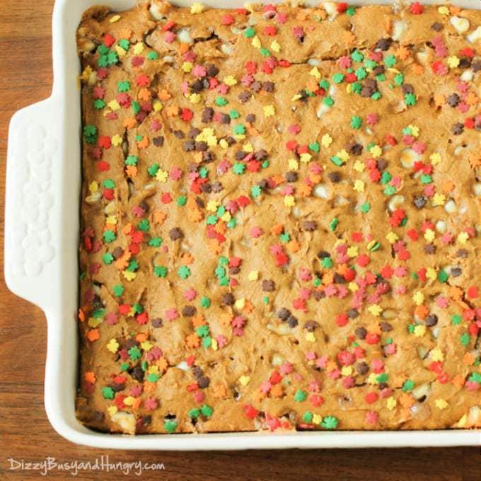 Overhead shot of white chocolate chip pumpkin cake in a white baking pan on a wooden table. 