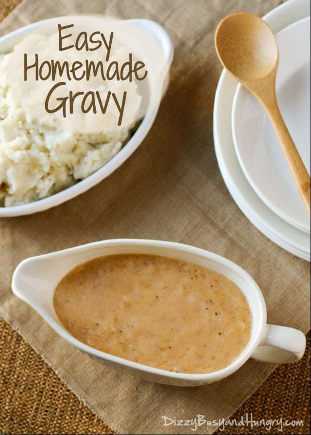 Overhead shot of homemade gravy in a white gravy boat with a bowl of mashed potatoes and a wooden spoon on the side. 