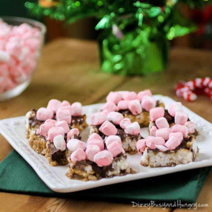 Side view of peppermint marshmallow rice cakes on a white plate with more marshmallows in the background. 