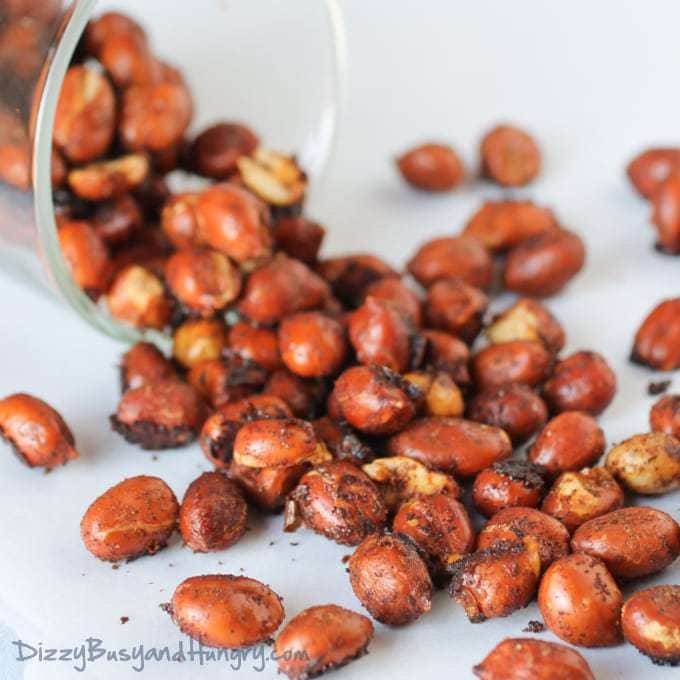 Close up shot of chipotle lime roasted peanuts spilled out of a clear glass. 
