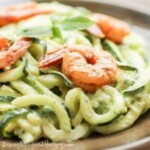 Close up shot of creamy avocado noodles with chipotle lime shrimp on a wooden plate.