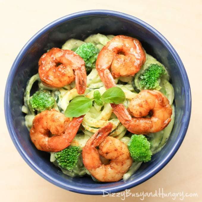 Close up shot of creamy avocado noodles with chipotle lime shrimp in a blue bowl.