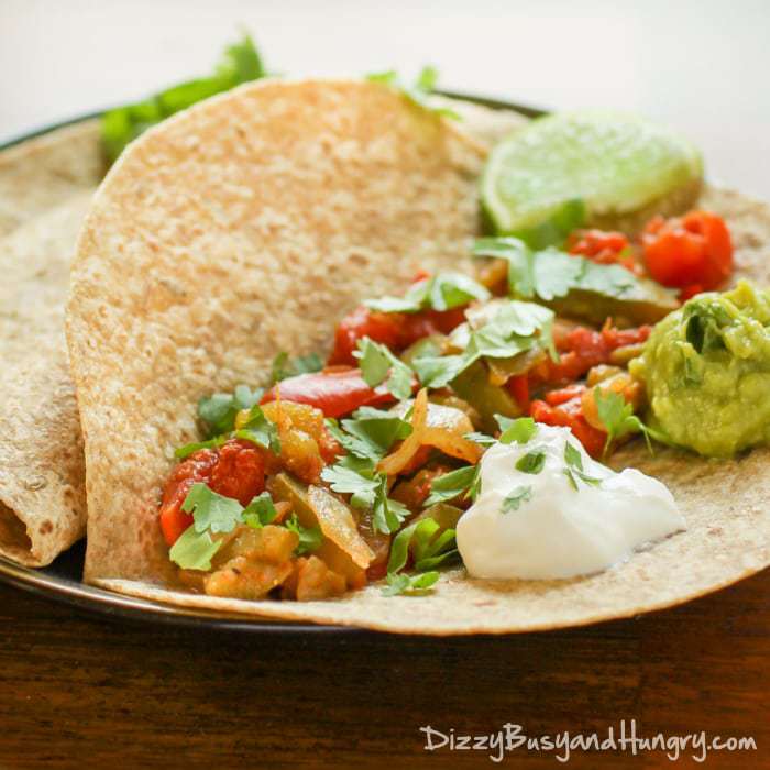 Close up shot of veggie fajitas open on a white plate on a wooden table.