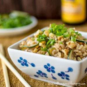 Side view of zucchini walnut fried rice in a white and blue bowl with chopsticks on the side.