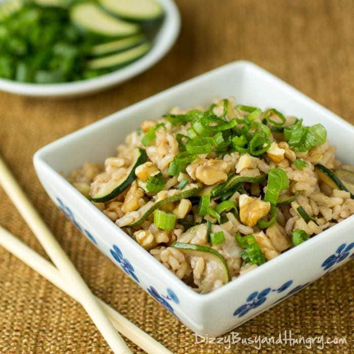 Side view of zucchini walnut fried rice in a white and blue bowl with chopsticks on the side. 
