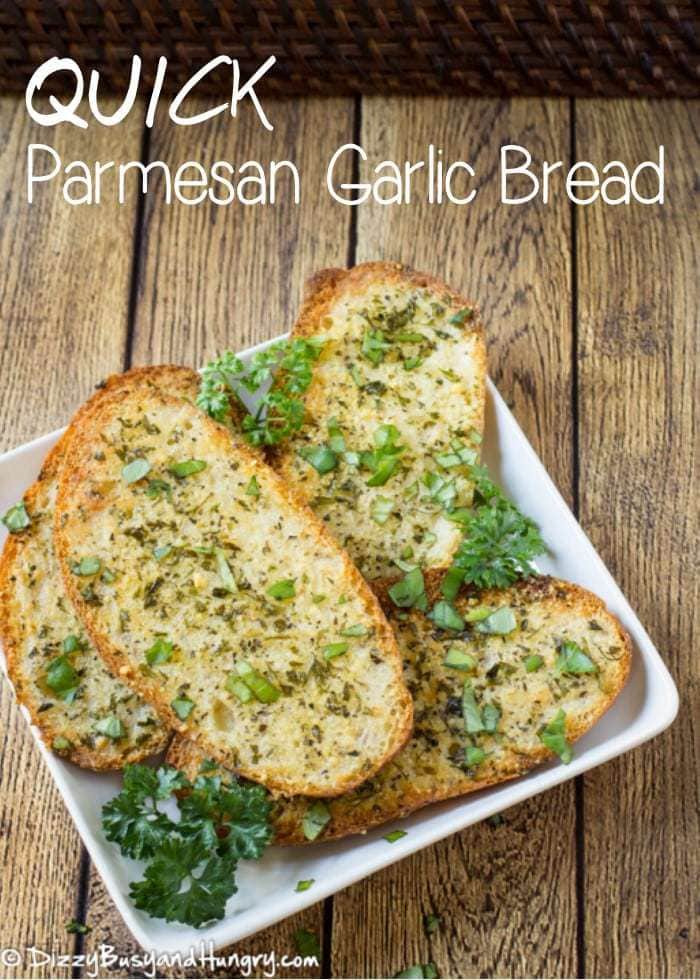 Overhead shot of Parmesan Garlic bread layered on a white plate on a wooden surface. 