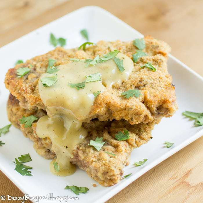 Overhead view of chicken fried steak on a white plate with yellow gravy.