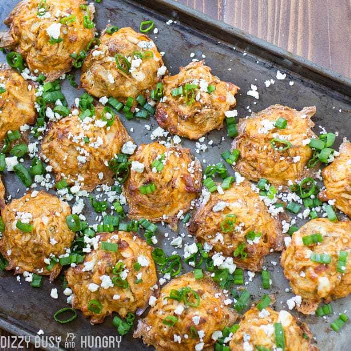 Overhead shot of buffalo blue cheese potato bites lines on a black baking sheet. 