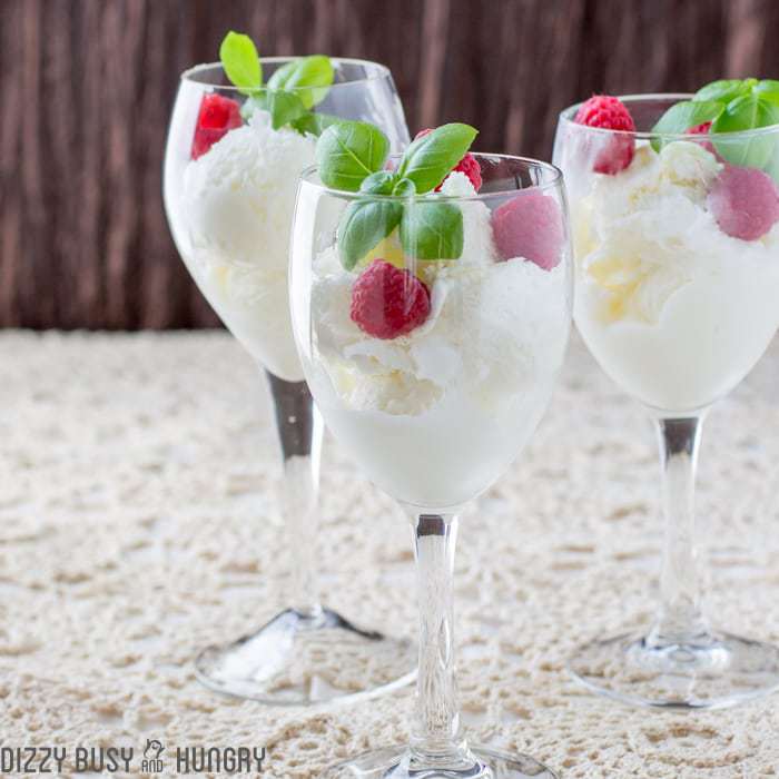 Side shot of moscato ice cream in three wine glasses garnished with mint and raspberries. 