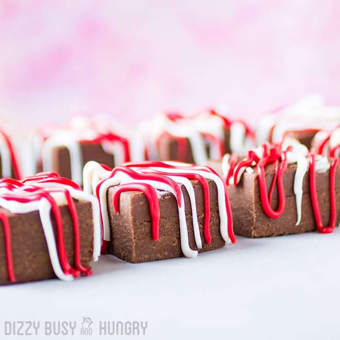 Side view of chocolate raspberry fudge pieces lined on a white surface. 