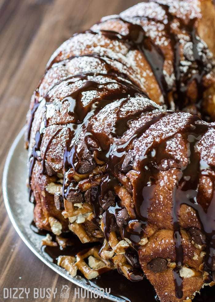 Close up shot of whole chocolate pretzel monkey bread on a white plate on a wooden table.