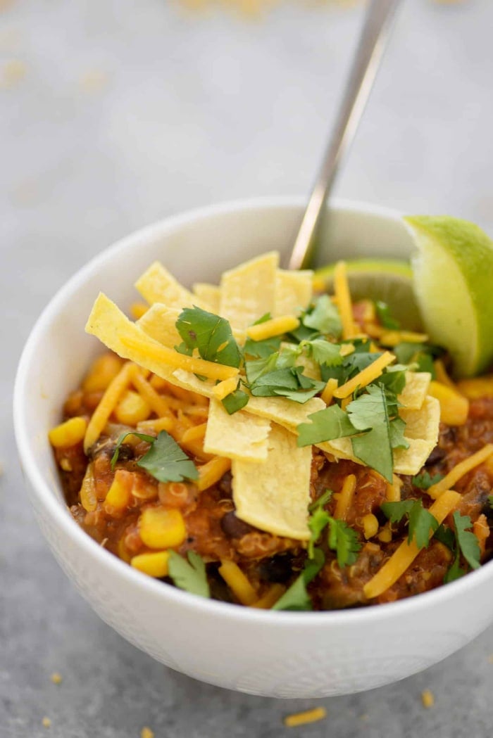 Side view of instant pot enchilada casserole in a white bowl with a spoon on the side. 