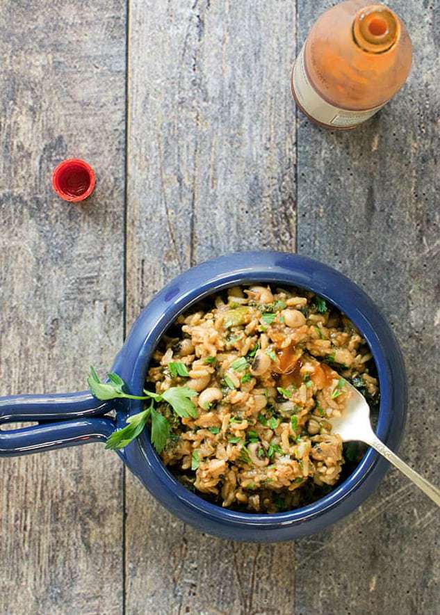 Overhead shot of vegan black eyed pea jambalaya in a blue bowl with a fork on the side. 