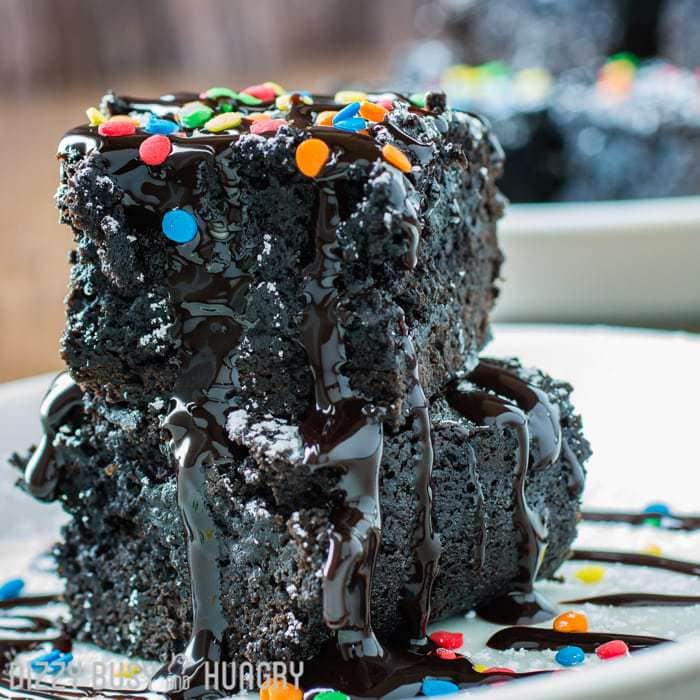 Side shot of two dark chocolate black bean brownies stacked on a white plate. 