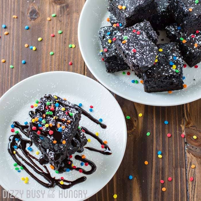 Overhead shot of a single dark chocolate black bean brownie on a white plate with more on a white plate in the background. 