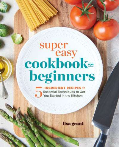 Close up shot of a sign that says \"Super easy cookbook for beginners\" on a white plate with vegetables surrounding it. 