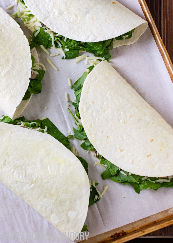 Overhead shot of multiple whole quesadillas on a baking sheet. 