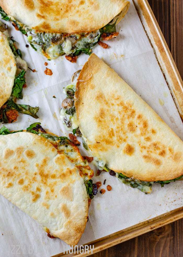 Overhead shot of multiple whole cooked quesadillas on a baking sheet. 