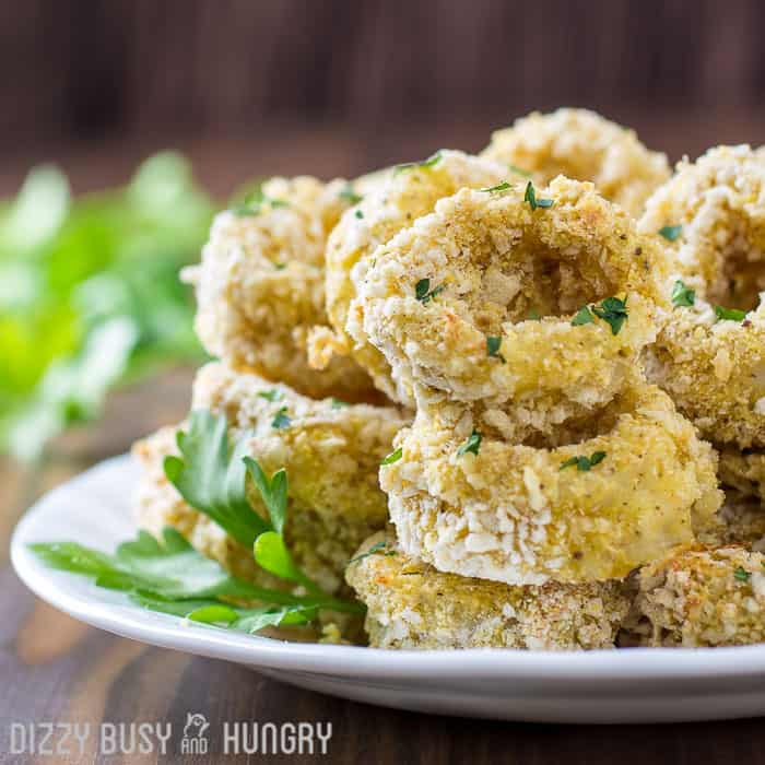 Sidovy av bakad calamari med örter på en vit tallrik på ett träbord.