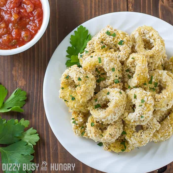 overhead of one of the easy seafood recipes - calamari - on a white plate with parsley garnish