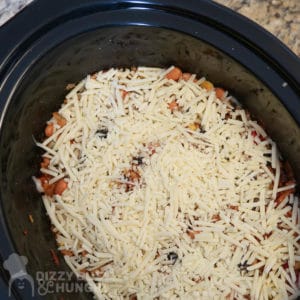 Overhead view of process shot- crock pot with shredded cheese added. 