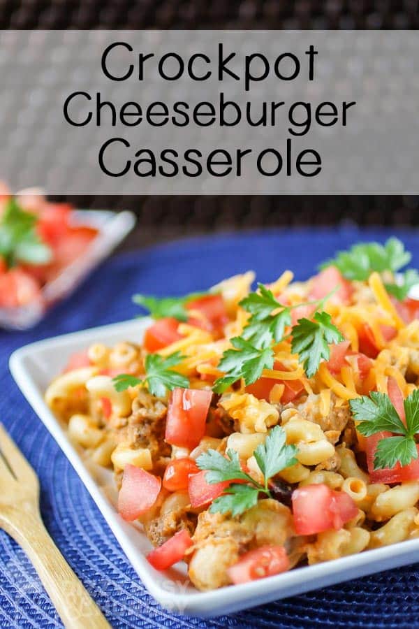 Close up shot of crockpot cheeseburger casserole on a white plate on a blue cloth with a wooden fork on the side. 