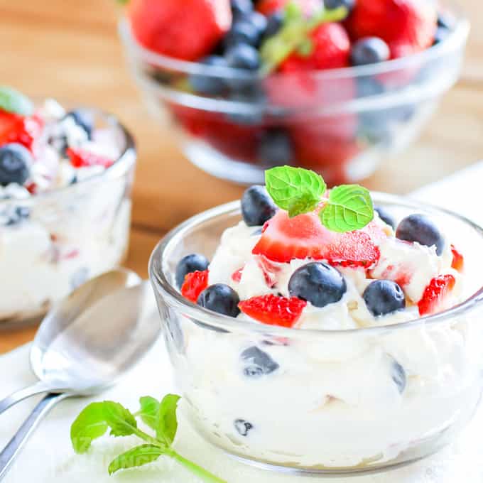 Cheesecake fluff in a bowl with a pretty basil garnish and two spoons to the left