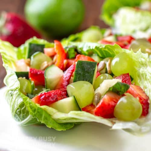 Close side view of finished veggie salad served on a white platter on a crisp green lettuce leaf.