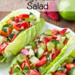 Fruit and vegetable salad spooned into romaine lettuce leaves and served on a white platter.