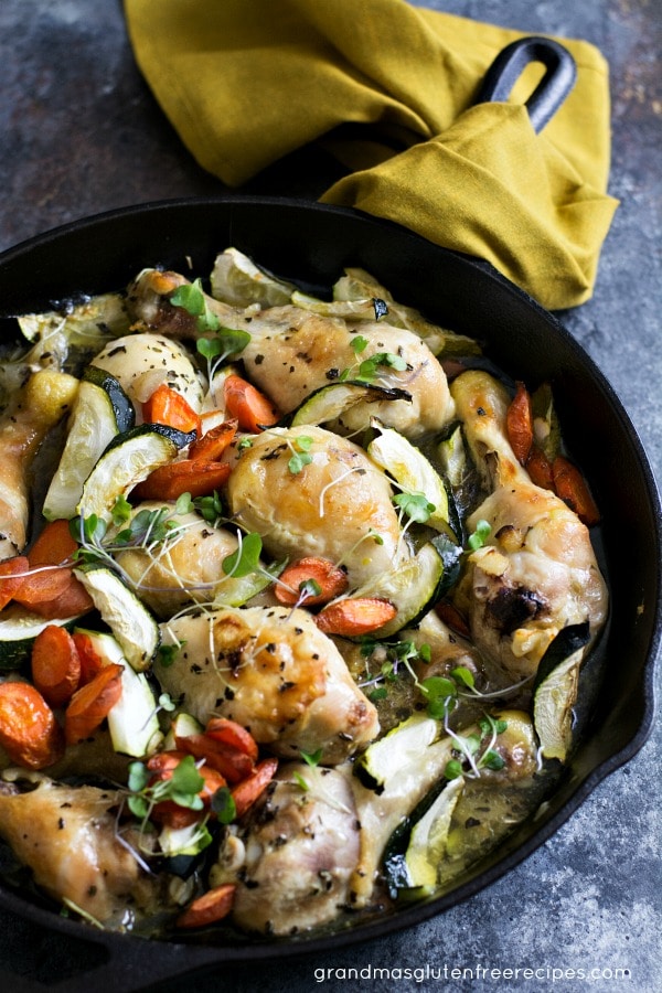 Overhead view of cooked chicken and veggies in a cast iron skillet. 