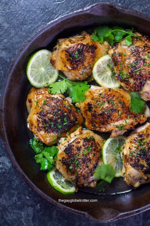Top view of crispy cooked chicken with lime wedges and cilantro for garnish - Cheap Chicken Recipes