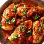 Top view of a stainless steel pan filled with cooked chicken in a tomato sauce - cheap chicken recipes