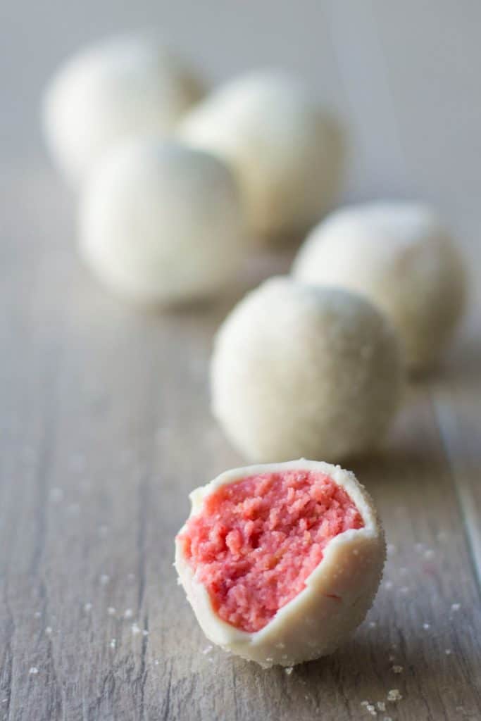 front view of a cake pop with white frosting and pink on the inside