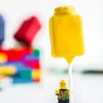 front view of a yellow lego man holding a yellow cake pop