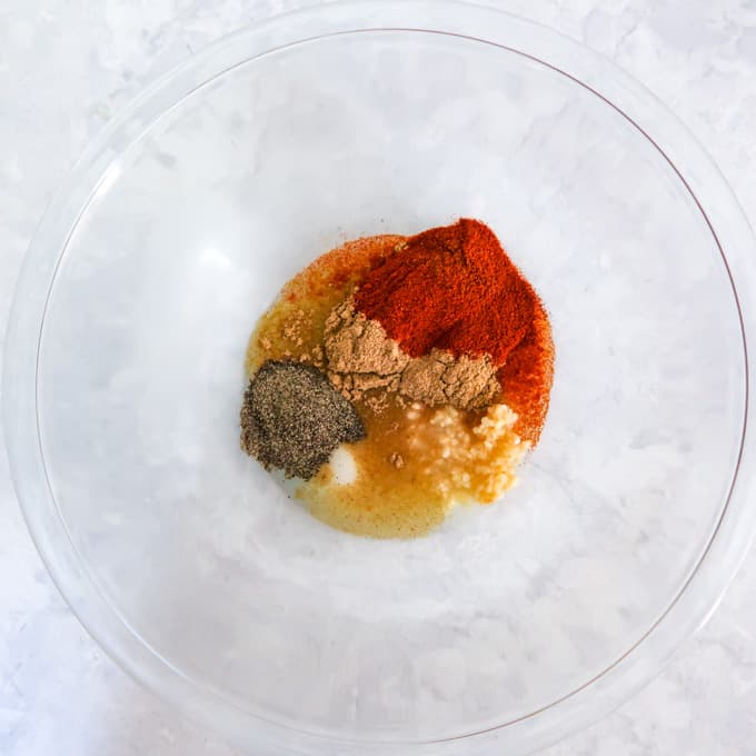 Overhead shot of clear bowl with ingredients combined to make marinade.