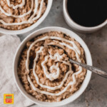 top view of steel cut oats in a white bowl with a simple cream cheese frosting swirl